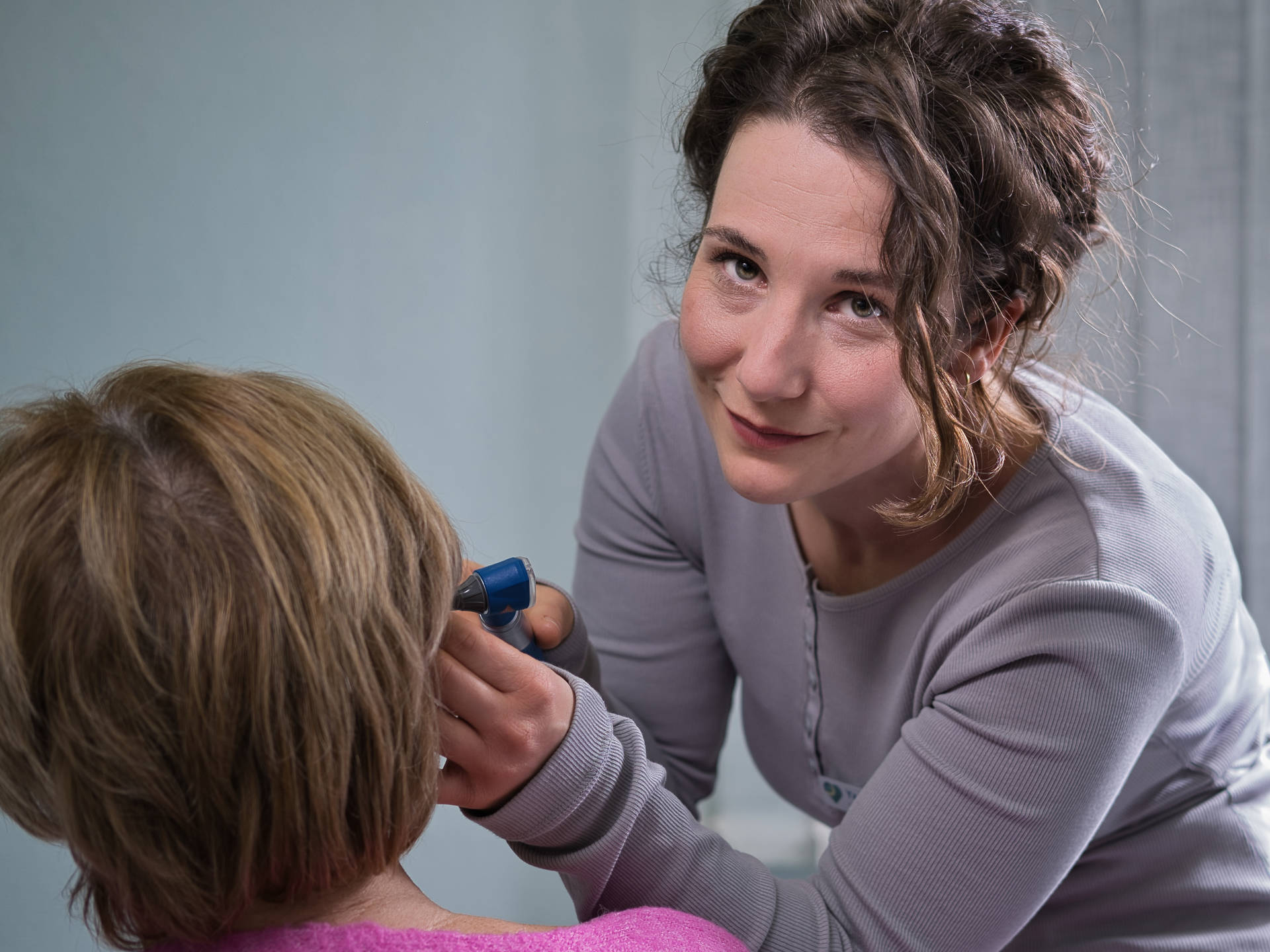 Foto einer Ärztin, die bei einer Patientin das rechte Ohr untersucht